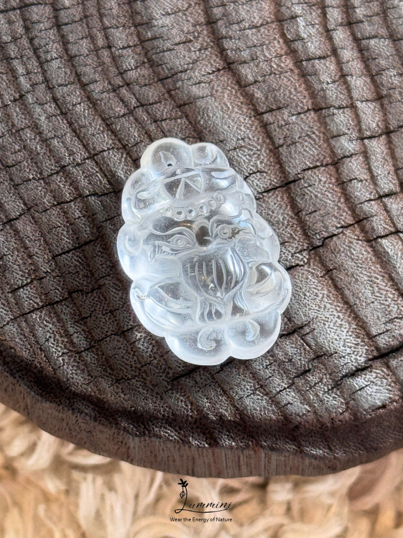 A carved translucent white jade pendant depicting a stylized animal face, resting on a textured dark brown wood slice background.