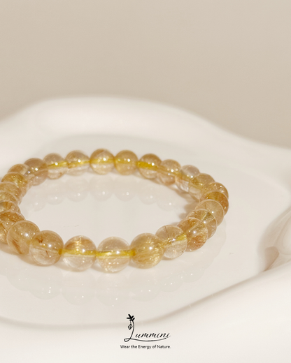 Yellow beaded bracelet on a white surface with 'Lummini' brand logo.